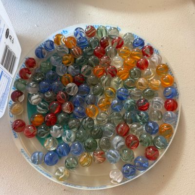 Sale Photo Thumbnail #79: Collection of vintage glass marbles with varied colorful swirl patterns, displayed in a clear plastic lid.