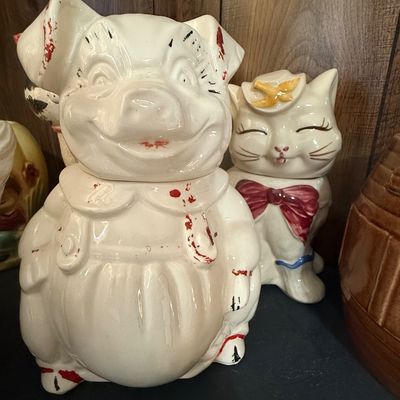 Sale Photo Thumbnail #34: Vintage Shawnee Pottery ceramic pig cookie jar with painted cold-paint accents, displayed alongside a smiling cat cookie jar.