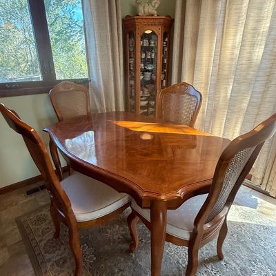 Sale Photo Thumbnail #62: French Provincial style dining table with a polished wood finish and four matching cane-back chairs with cushioned seats.