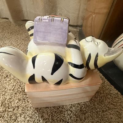 Sale Photo Thumbnail #29: Whimsical ceramic cookie jar featuring a striped cat lying on a stack of books and reading, with a glossy painted finish.