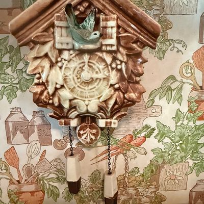 Sale Photo Thumbnail #16: Vintage ceramic cuckoo clock-style wall pocket planter featuring a bluebird perched above the clock face and decorative ceramic weights on chains.