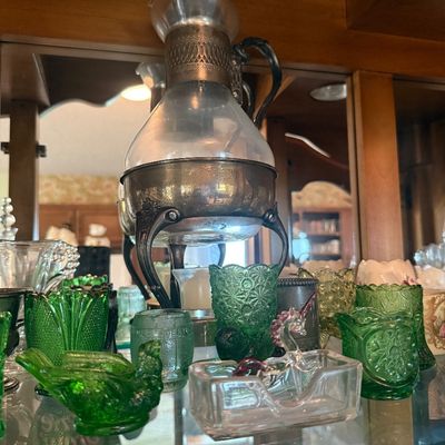 Sale Photo Thumbnail #96: Vintage glass and silver-tone metal decanter on a warmer stand, surrounded by an array of green depression glass toothpicks and small collectibles.