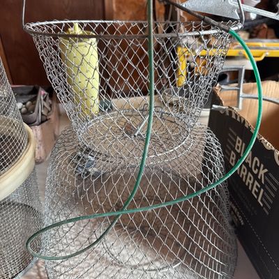 Sale Photo Thumbnail #77: Vintage collapsible wire mesh fishing basket with green carrying wire and spring-loaded hatch.