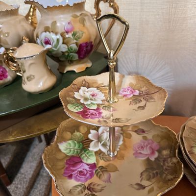 Sale Photo Thumbnail #97: Vintage two-tiered hand-painted porcelain dessert stand featuring a pink and white rose motif with a gold-tone handle, displayed alongside matching tea set pieces.
