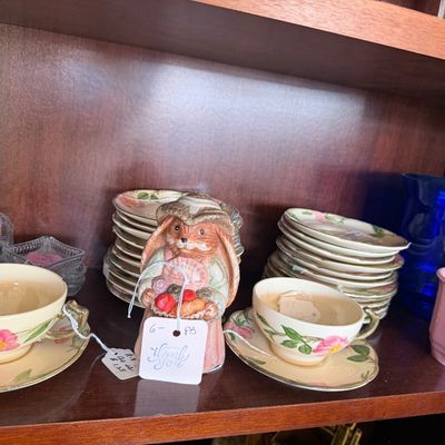 Franciscan Desert Rose china tea cups and saucers displayed alongside a ceramic rabbit figurine on a wooden shelf.