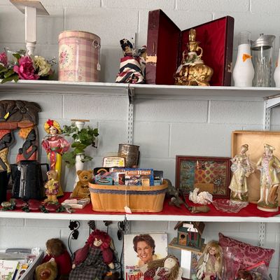 Shelves filled with various home decor items, including rag dolls, teddy bears, decorative figurines, books, and a woven basket.