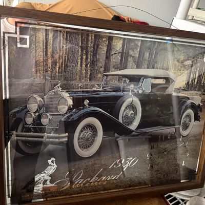 Framed wall clock featuring a black-and-white photograph of a 1930 Packard automobile with a wood-look frame.