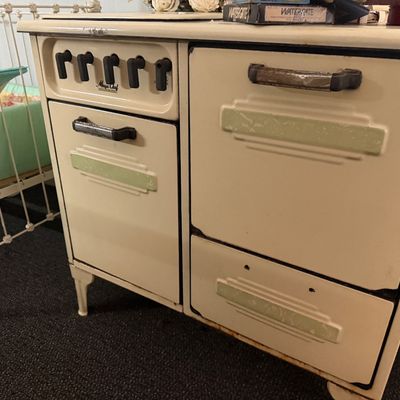 Vintage Magic Chef cream enamel gas stove featuring Art Deco style green trim and black control knobs.