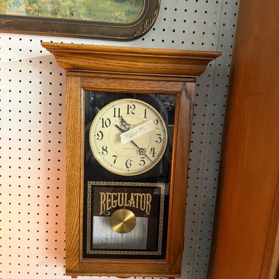 Vintage oak schoolhouse regulator wall clock with a brass pendulum and glass front display.