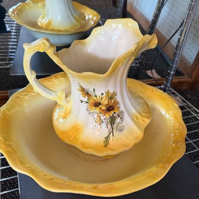Vintage ceramic pitcher and wash basin set featuring yellow shaded rims, molded scrolled details, and a sunflower graphic.