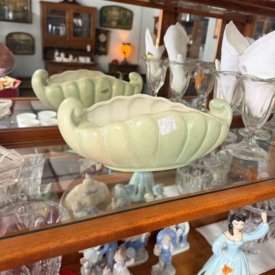 Vintage light green art pottery console bowl with scrolled handles and ribbed sides, displayed in a wooden curio cabinet.