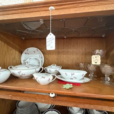 Vintage oak Barrister-style bookshelf cabinet filled with fine china tableware with pink floral motifs and glass dessert cups.
