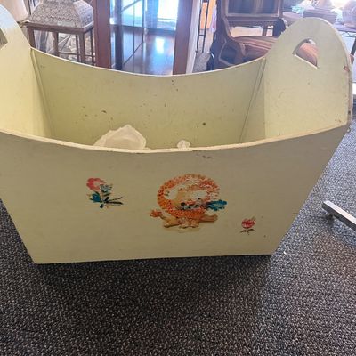 Vintage pale yellow painted wooden tote box featuring handle cutouts and decal illustrations of a lion and flowers.