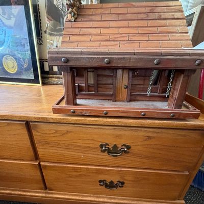 Handcrafted wooden log cabin birdhouse or decorative structure featuring a shingled roof and stone chimney, sitting atop a vintage wooden...