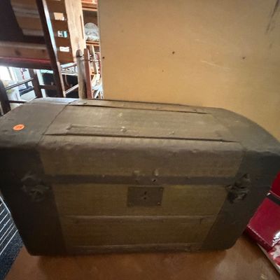 Antique dome-top steamer trunk featuring wood slats, dark metal banding, and original hardware with visible age-related wear.