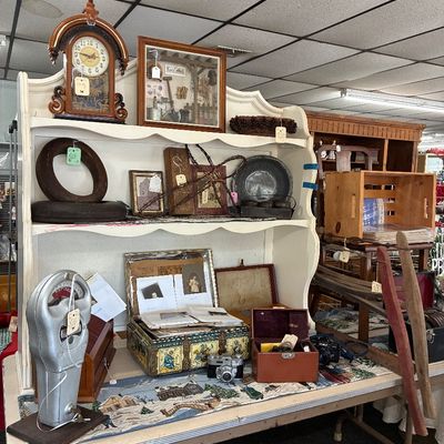 Vintage items displayed on a white hutch, including a vintage parking meter, mantels, decorative clock, framed shadow box, and photo albums.