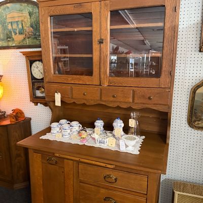 Vintage oak step-back hutch featuring upper glass-front cabinet doors, small drawers, and a lower base with drawers and a side cabinet.