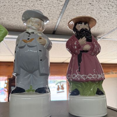 Pair of vintage ceramic character decanters featuring novelty figures with glazed finishes.