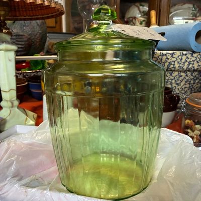 Vintage green uranium glass storage canister with a matching faceted finial lid, featuring a ribbed glass body.