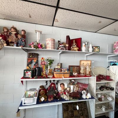 Shelves filled with various collectibles including porcelain and cloth dolls, teddy bears, figurines, decorative tins, and tea sets.
