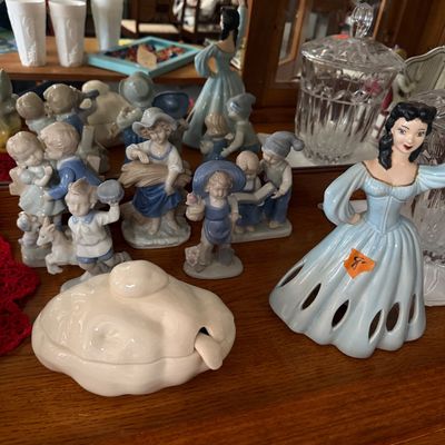 Collection of vintage porcelain figurines, including various blue-and-white children figures and a lady in a blue gown dress ceramic bell.