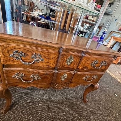 French Provincial style wood bombe chest with ornate brass hardware and cabriole legs.