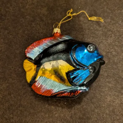Sale Photo Thumbnail #77: Blown glass tropical fish Christmas ornament featuring vibrant blue, yellow, black, and red accents with a gold hanging cord.