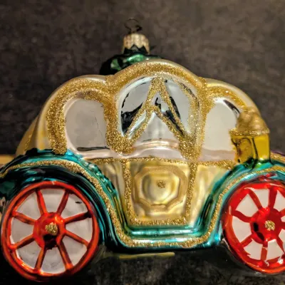 Sale Photo Thumbnail #74: Blown glass carriage Christmas ornament decorated with gold glitter detailing and painted wheels.