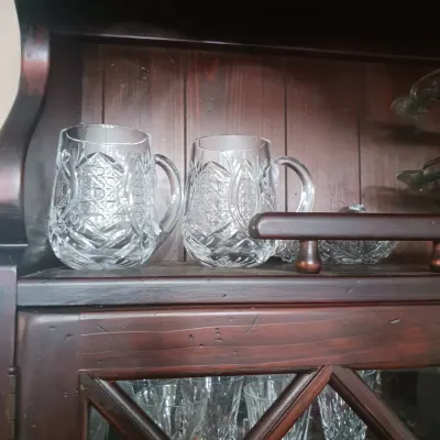 Sale Photo Thumbnail #23: Pair of vintage cut crystal pitchers with geometric patterns, displayed on a wooden cabinet shelf.