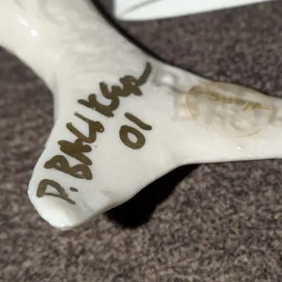Sale Photo Thumbnail #52: Detail view of the artist signature 'P. Walker 01' on the base of a white porcelain or ceramic figurine.