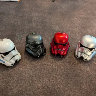 Sale Photo Thumbnail #68: Set of four Star Wars Stormtrooper helmet holiday ornaments in white, metallic gunmetal grey, red, and silver finishes.