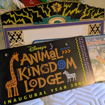 Sale Photo Thumbnail #65: Disney memorabilia lot including a 2001 Disney's Animal Kingdom Lodge Inaugural Year novelty license plate, a Tower of Terror themed photo frame, and a Walt Disney World item.