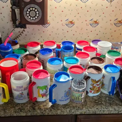 Sale Photo Thumbnail #14: Large collection of vintage Disney character plastic travel mugs, souvenir cups, and a Halloween cauldron popcorn bucket.