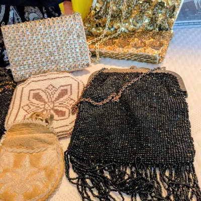 Sale Photo Thumbnail #84: Collection of vintage beaded and sequined evening purses, featuring a black micro-beaded bag with long fringe, a gold sequin clutch, and various smaller coin pouches.