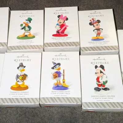 Sale Photo Thumbnail #64: Collection of nine boxed Hallmark Keepsake Disney ornaments from 'A Year of Disney Magic' series, featuring characters like Mickey, Minnie, Donald, and Goofy in seasonal themes.