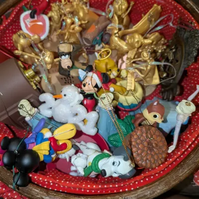 Sale Photo Thumbnail #38: Collection of Disney and holiday Christmas ornaments filling a red fabric-lined woven basket, featuring characters like Mickey Mouse, Goofy, Winnie the Pooh, and 101 Dalmatians.