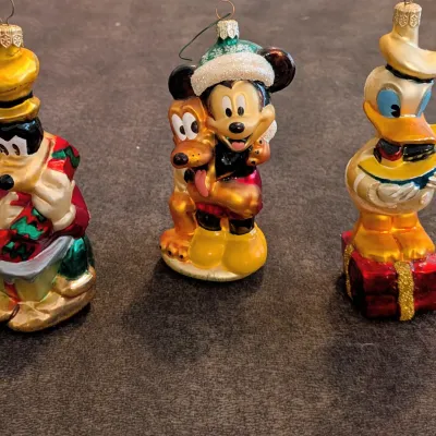 Sale Photo Thumbnail #71: Set of three Disney blow-glass Christmas ornaments featuring Goofy, Mickey Mouse with Pluto, and Donald Duck with glitter accents.