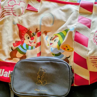 Sale Photo Thumbnail #81: Disney holiday tote bag featuring Chip and Dale painting a candy cane, paired with a black Disney x Pandora crossbody bag.