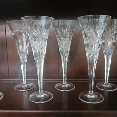 Sale Photo Thumbnail #2: Set of five cut Waterford crystal champagne flutes featuring intricate starburst and geometric patterns on slender stems.