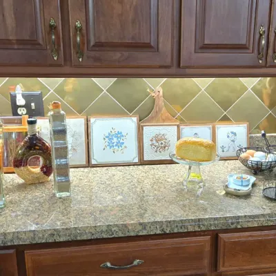 Sale Photo Thumbnail #13: Kitchen countertop display featuring decorative tiles, vintage glassware, decorative bottles filled with grains and spices, wire organizers, and a wooden knife block.