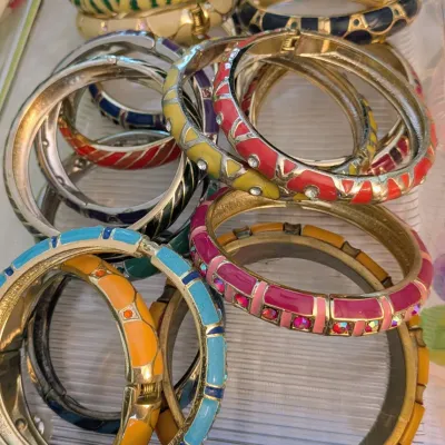 Sale Photo Thumbnail #90: Collection of colorful enamel and rhinestone hinge bangle bracelets in a plastic organizer tray.