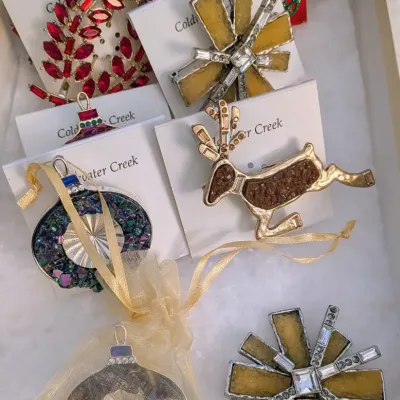 Sale Photo Thumbnail #91: Collection of holiday-themed brooches and ornaments, including Coldwater Creek brand items with rhinestones, glitter accents, and a leaping reindeer design.