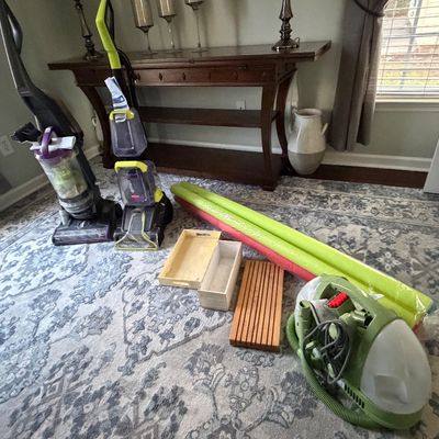 Selection of household items including Bissell upright vacuums, a portable carpet cleaner, wooden organizer trays, pool noodles, and a...