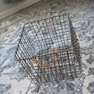 Modern dark wire storage basket featuring copper-toned handles,