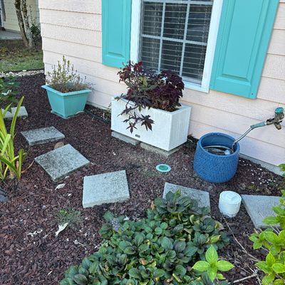 Collection of outdoor garden decor including a rectangular white concrete planter, a blue glazed hose pot, and a teal plastic planter.