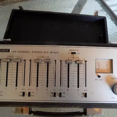 Vintage Sony MX-12 six-channel stereo microphone mixer in a portable black hard shell case, featuring dual VU meters and slider controls.