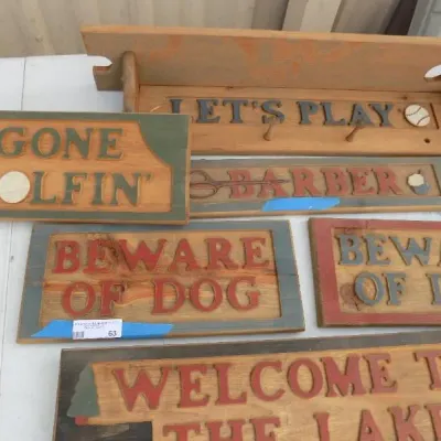 Collection of vintage-style carved wooden novelty signs and a matching coat rack shelf, featuring painted lettering and themed graphics.