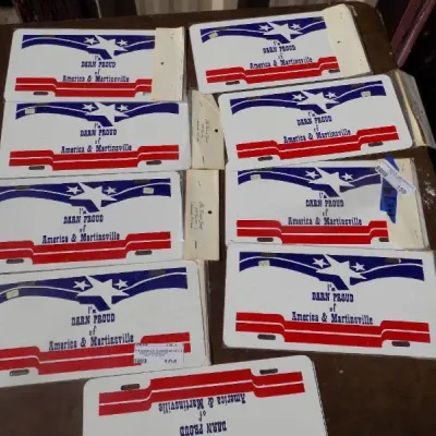 Collection of vintage novelty license plates reading 'I'm Darn Proud of America & Martinsville' in patriotic red,...