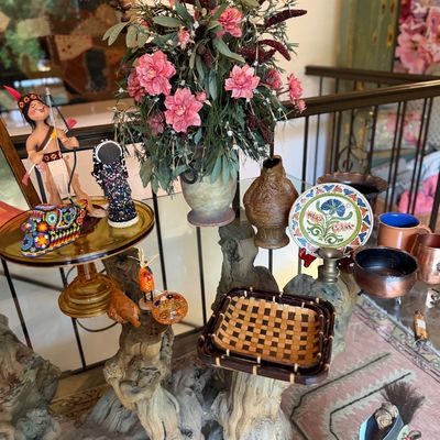 Collection of rustic and artisanal home decor items, including a driftwood table base, woven baskets, beaded figurines, ceramic vessels,...