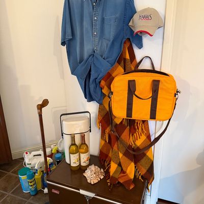 Collection of miscellaneous items including a vintage brown metal Coleman cooler, a bright yellow shoulder bag, a plaid throw blanket, a...